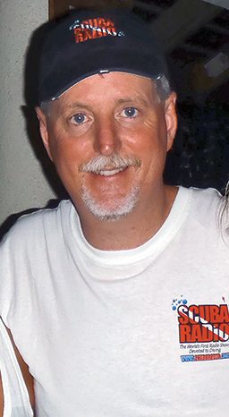 Headshot of Greg Holt wearing white T-shirt and ball cap