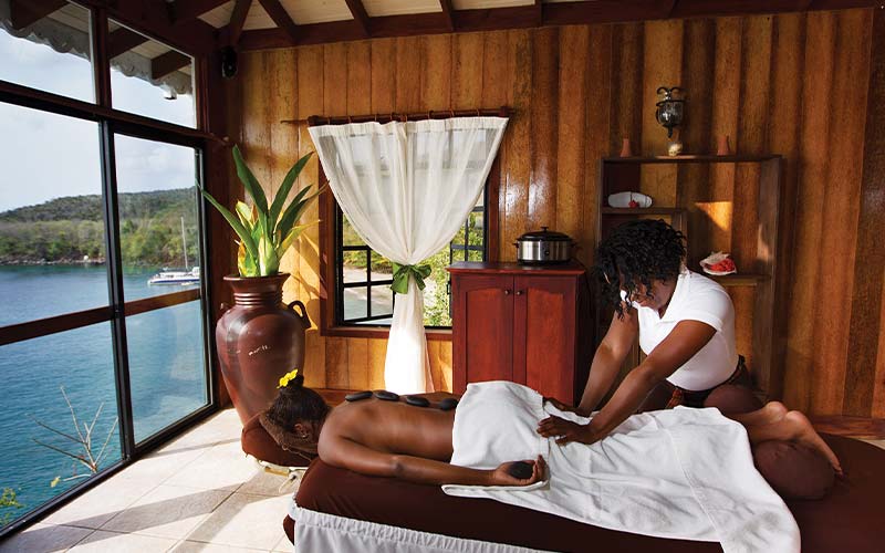 Person gets a massage in a wood-paneled room that overlooks the water