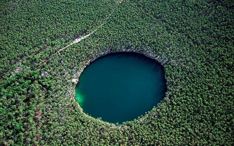 Aerial view of a giant blue circle lake in the middle of trees