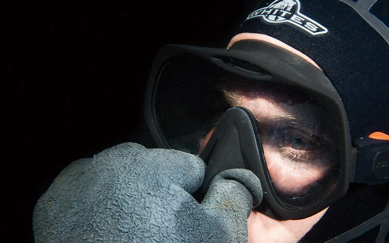 Diver plugs his nose while wearing mask
