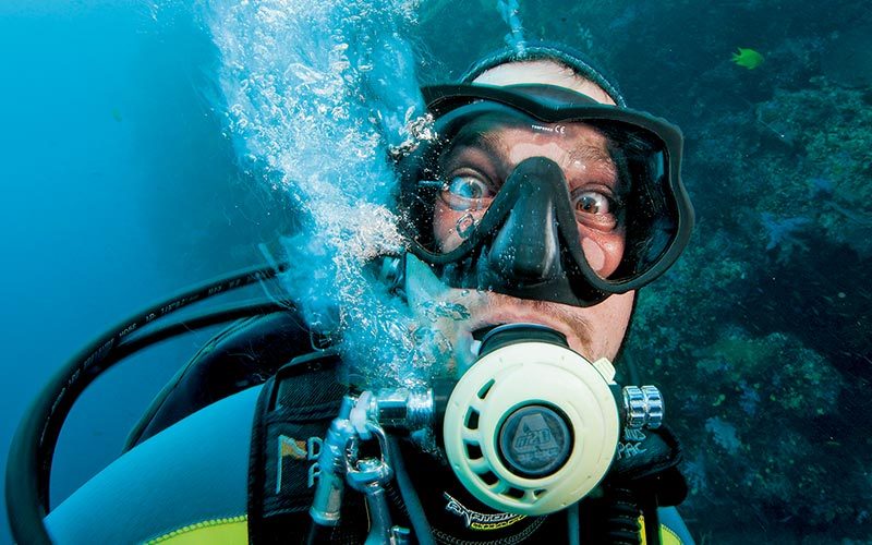 Surprised diver blows bubbles out regulator