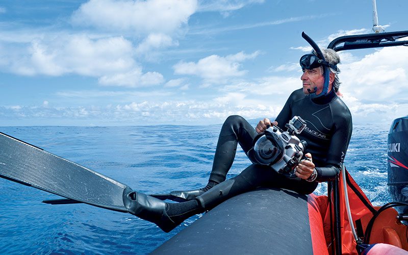 Freedive photographer prepares to slide into water off of boat