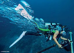 Diver holding gear is surrounded by bubbles