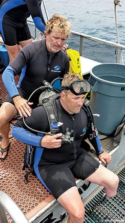 John Thompson helps a diver into his gear