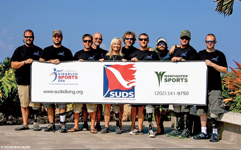 A group of SUDS divers hold a sign and pose for a group photo in sunny Kona