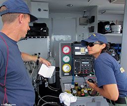 Two people on a boat monitor a diver who swims in the ocean