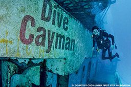 Male diver floats near Cayman sign