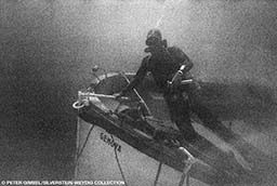 Old grainy image of a diver next to a sunken dive boat