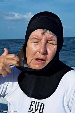 Old woman in a dive hood pulls at it