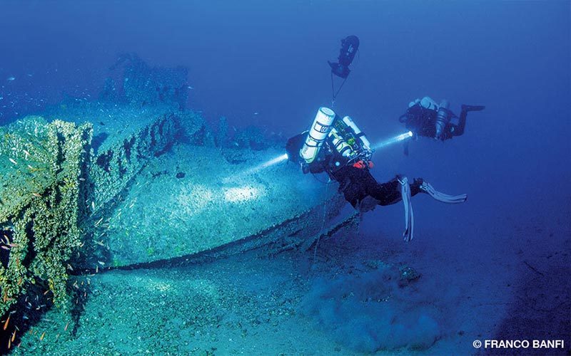 Two divers explore an old shipwreck