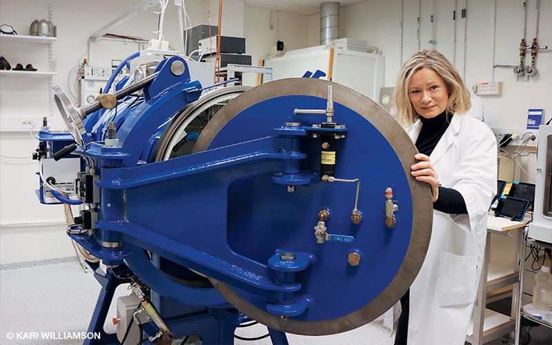 Ingrid Eftedal, Ph.D., stands beside a small hyperbaric chamber used for animal studies.