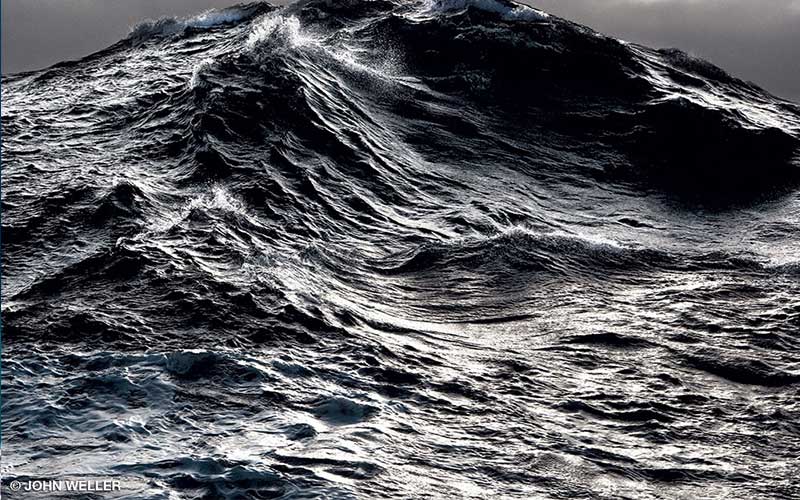 A close-up photo of a dark, huge ocean wave