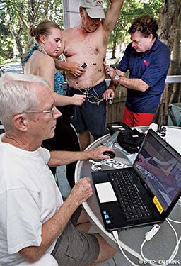 A topless man in a baseball cap gets hooked up for an EKG