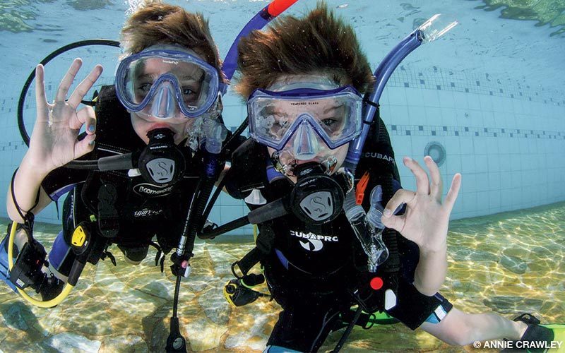 Two young divers have fun working on their buoyancy control and demonstrating hand signals.