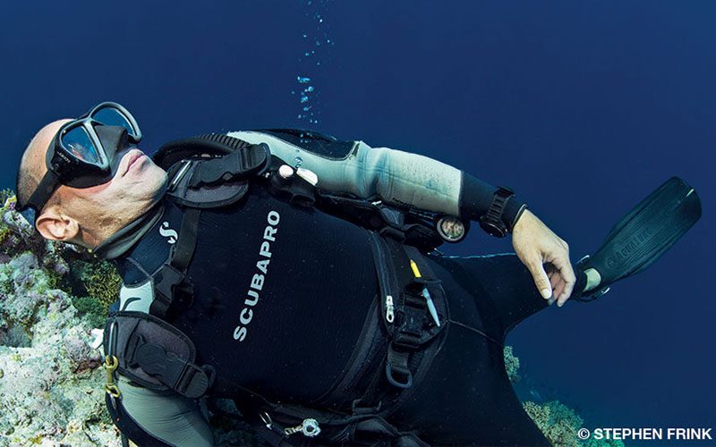 An unconscious diver floats near coral
