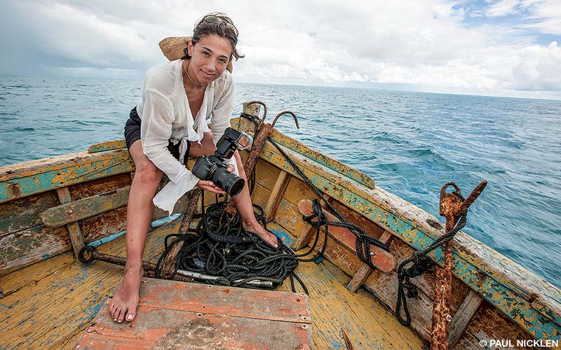 Christina Mittermeier poses on a boat while holding a large digital camera