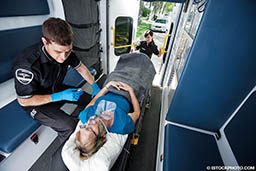 A male EMT treats a female patient. They are in an ambulance.