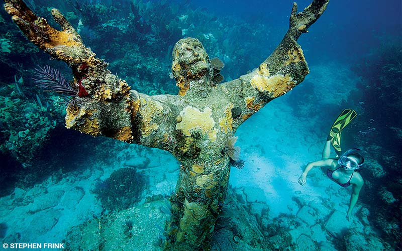 A female snorkeler swims near Christ of the Abyss statue