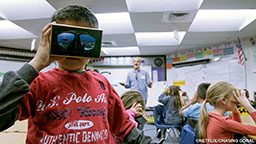 A little boy in a red T-shirt holds a king of view finder to his eyes