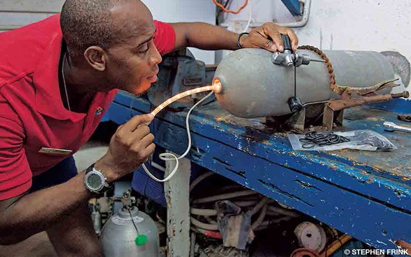 A Black man inspects a cylinder with a tiny rope light