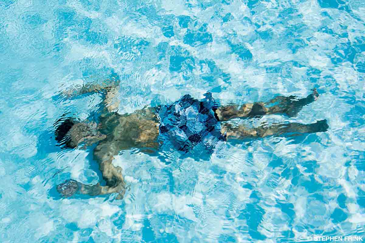 A man in blue swimming trunks is fully submerged in a pool.