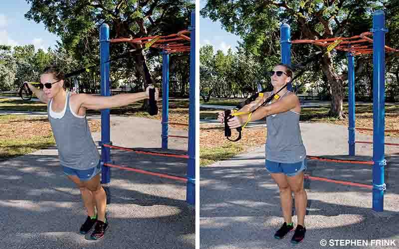 A female personal trainer demonstrates chest flies using a suspension trainer.