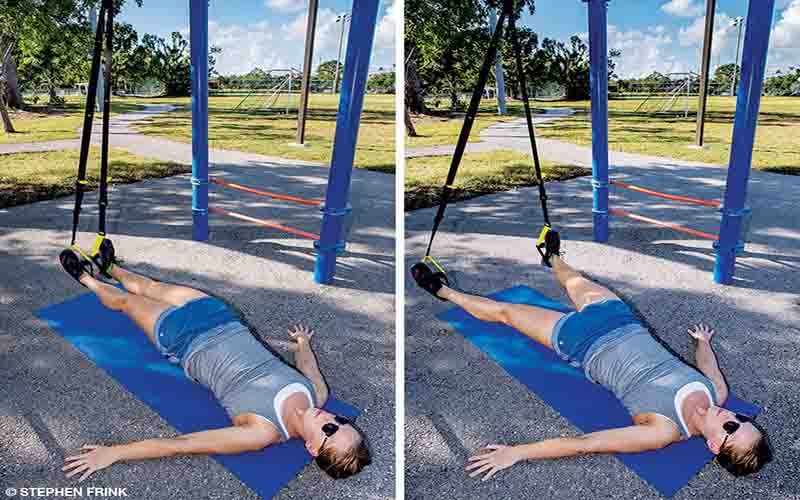 A female personal trainer does a hip extension exercise via a suspension trainer. 