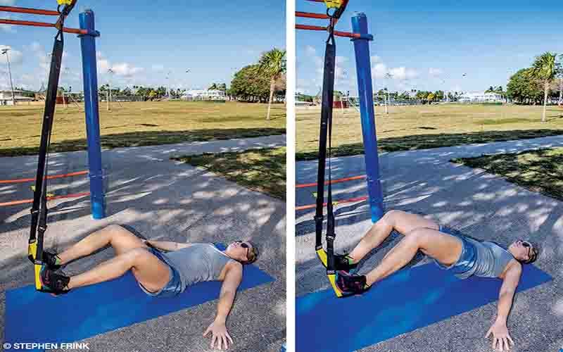 A female personal trainer performs a hip adduction using a suspension trainer.