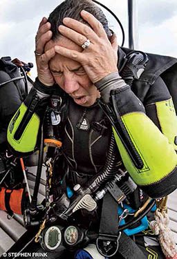 A female diver holds her head dramatically because she has a headache.