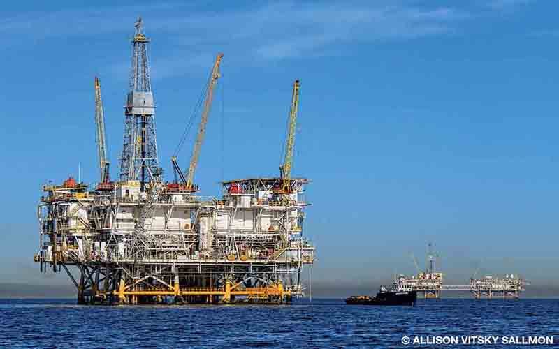 A giant oil rig stands in the middle of the ocean.