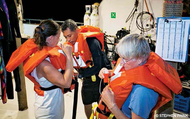 Three people don their life vests.