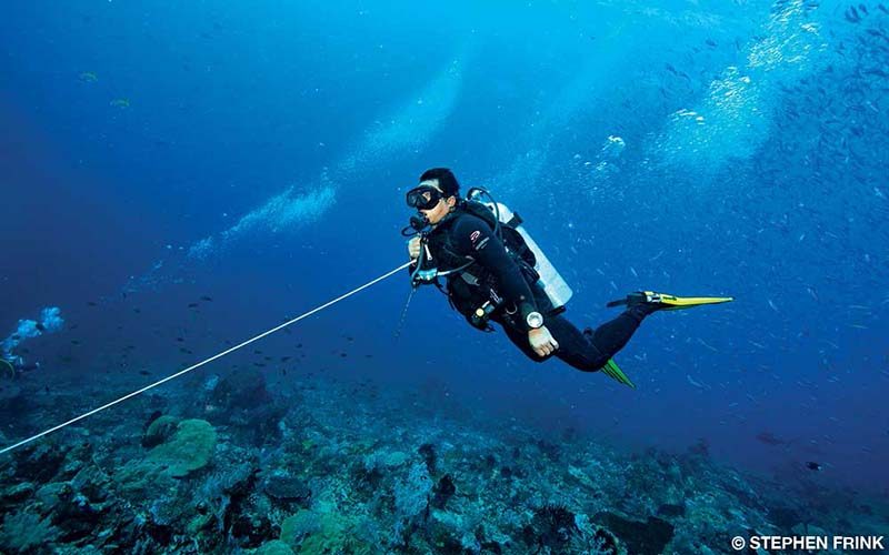 A diver swims along, assisted by a tether.