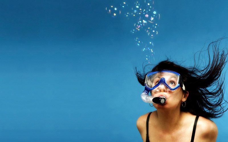 In a stock image, a female snorkeler is surrounded by blue waters
