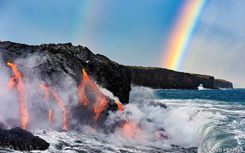 Hot lava spews out of a rock facing but in the background is a bright rainbow