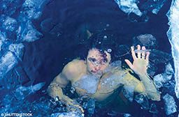 A shirtless man is underwater and looks terrified. 