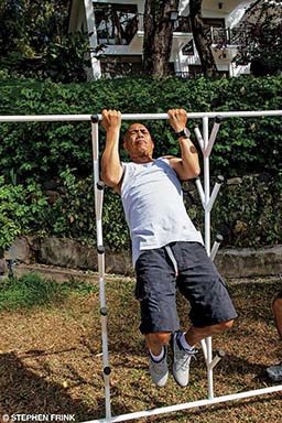 A man does pull-up exercises at a park.