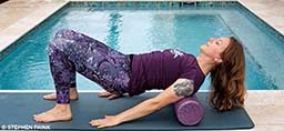 A woman demonstrates how to roll out the upper back with a foam roller.