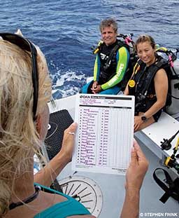 A dive operator checks a list to ensure all divers are on board.