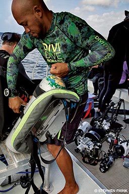 A Black diver readies his backplate before heading into the water