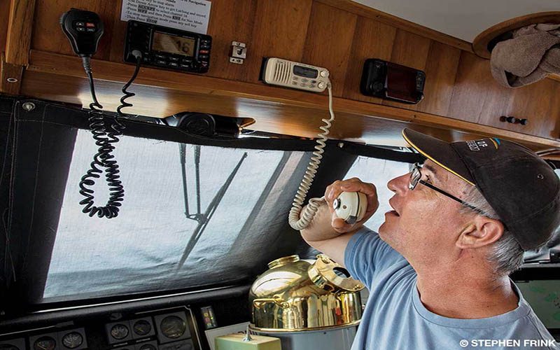 A man in a ball cap is radioing for help while on his boat