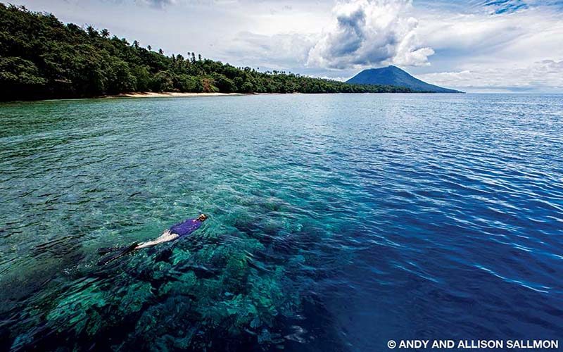 A snorkeler explores the pristine reefs of the Bunaken National Park in the shadow of Manado Tua volcano.