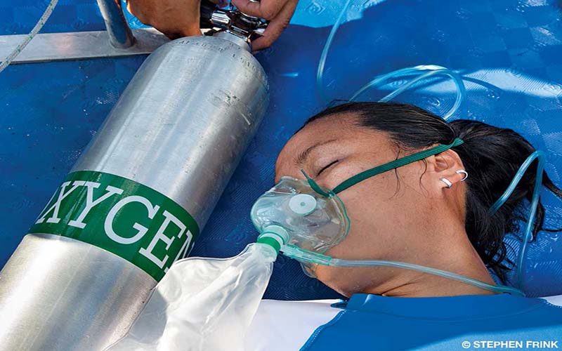 A woman is wearing a mask to be on an oxygen tank