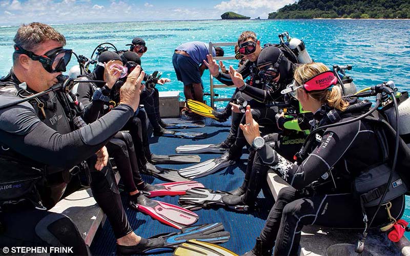 Group of divers on boat practice hand signals