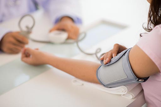 doctor measures woman's BP using a blood pressure cuff