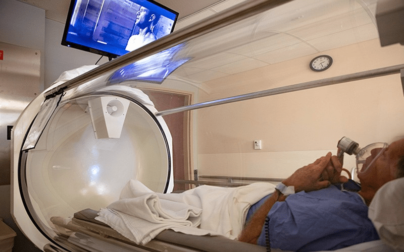 A man rests in a hyperbaric chamber and watches television
