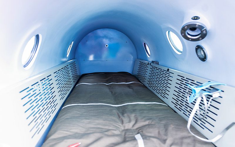 The inside of a hyperbaric chamber is padded and no one is in it.