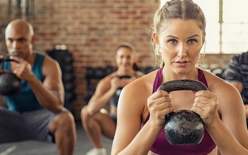 A woman holds a kettlebell in a fitness class