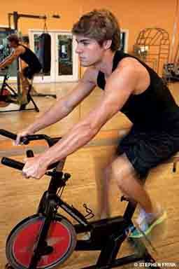 A young man rides an exercise bike. 