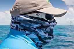 A man is wearing a hat, sunglasses and buff to protect against the sun.