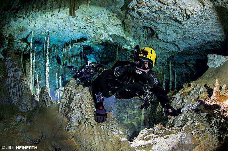 Two divers swim through a cave.